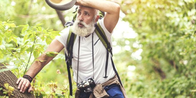 a healthy-looking man feeling exhausted on a hike in the woods