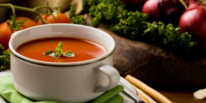 a bowl of soup surrounded by fresh vegetables