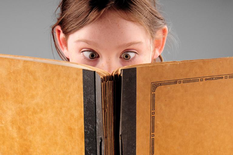 a cross-eyed child reading a book