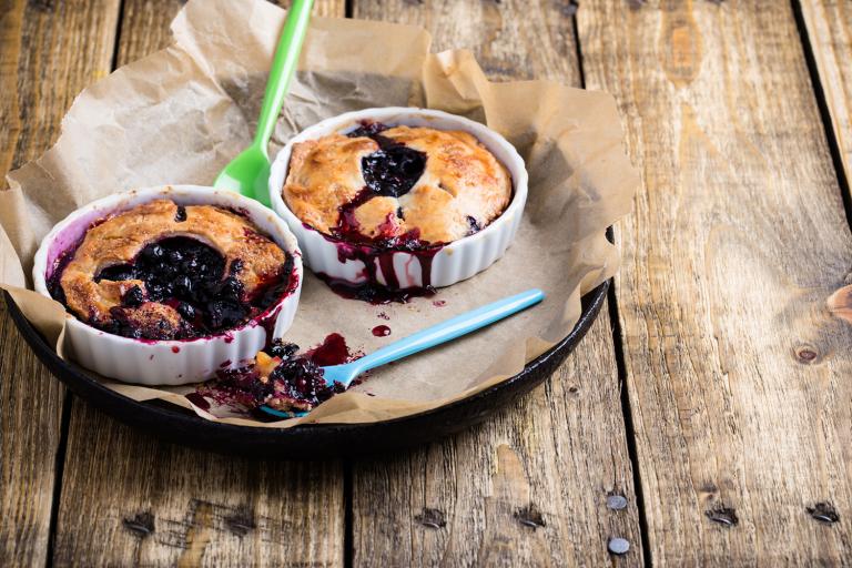 Individual blueberry pies on a rustic wooden table.