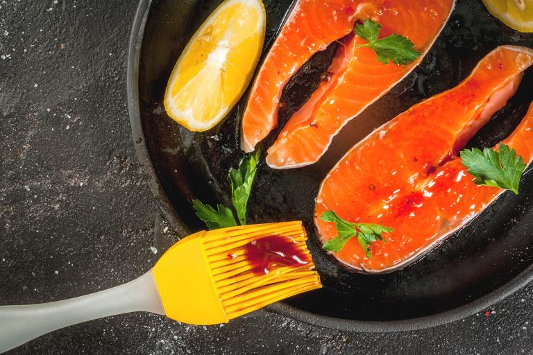 salmon being slathered with sauce for the grill